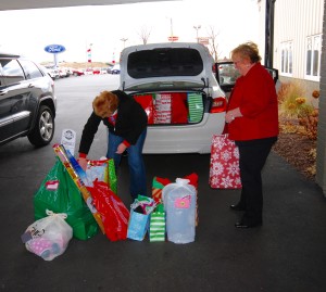 Car full of christmas presents with women and christmas presents in front of it